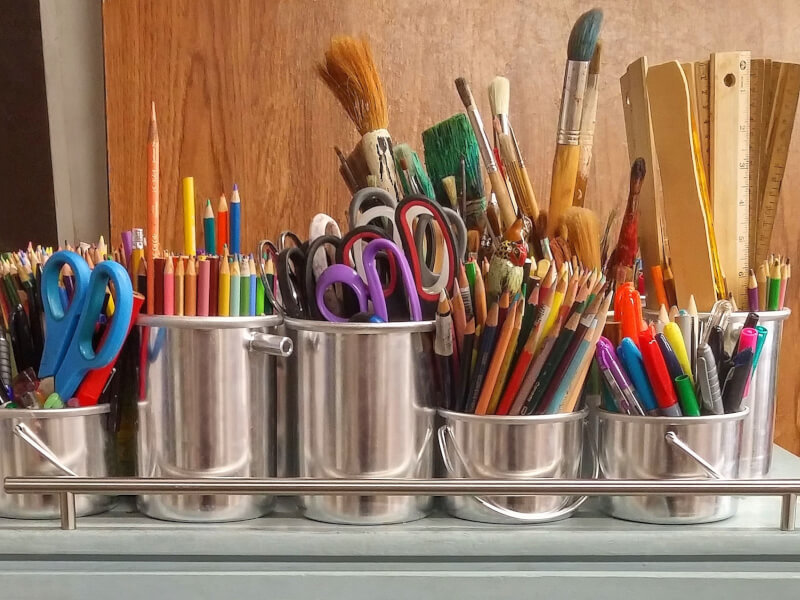 Several silver pots full of brushes, pens, pencils and scissors ready for crafting